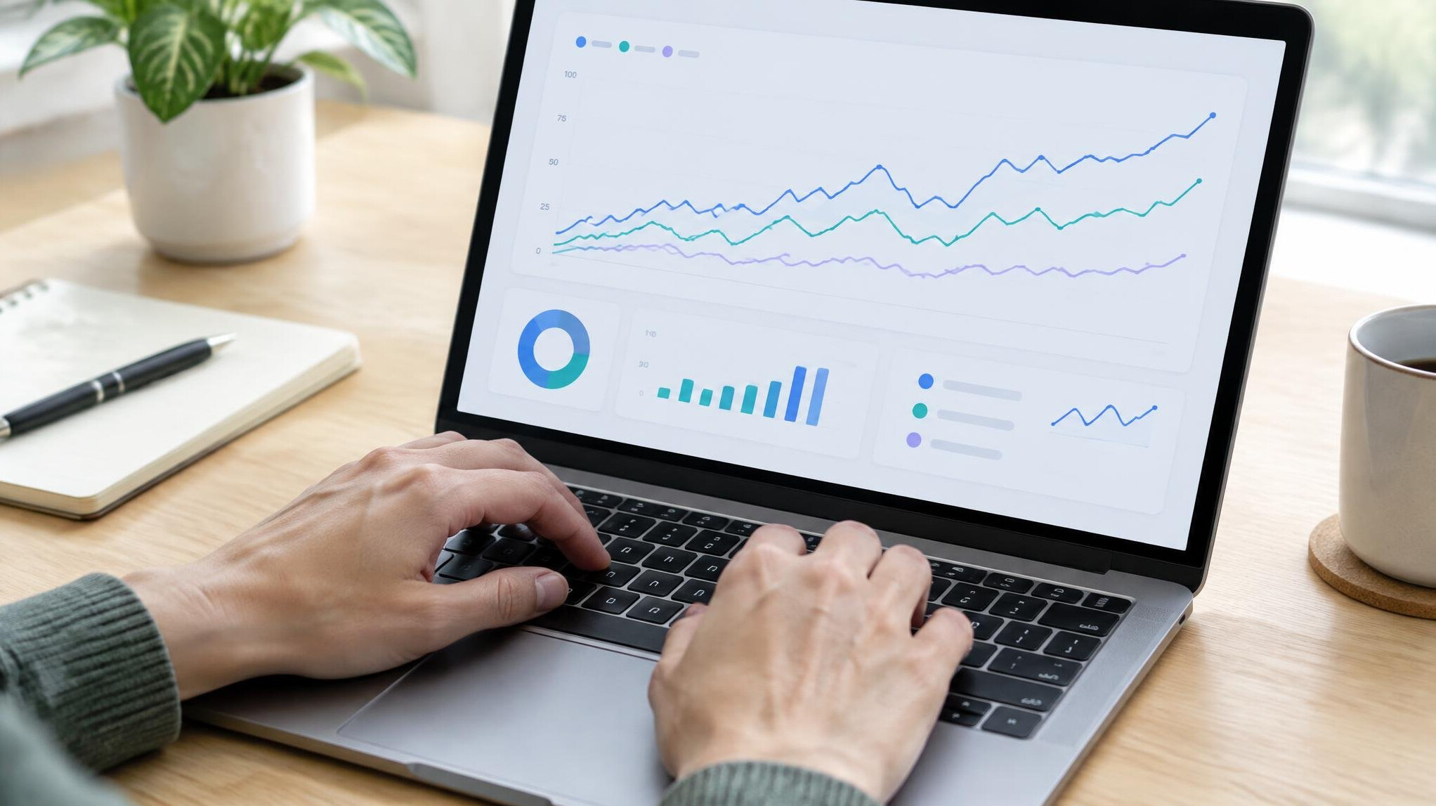 Hands typing on laptop showing data charts